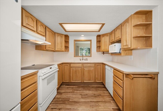 kitchen with open shelves, wood finished floors, a sink, white appliances, and under cabinet range hood