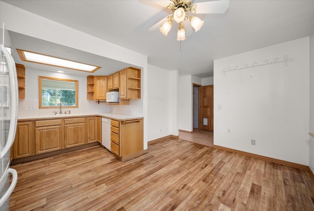 kitchen featuring open shelves, a sink, light wood-style flooring, white appliances, and light countertops