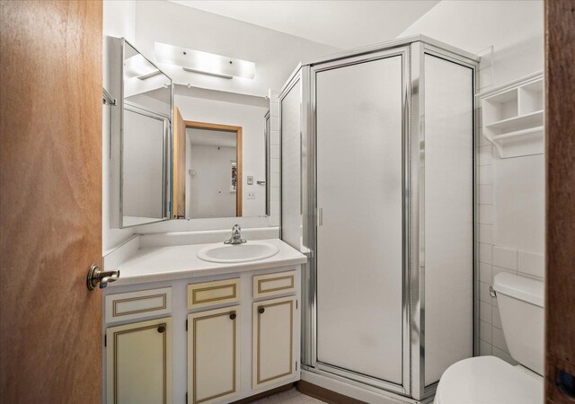 full bath featuring vanity, a shower stall, and toilet