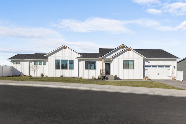 modern inspired farmhouse with an attached garage, fence, board and batten siding, and driveway