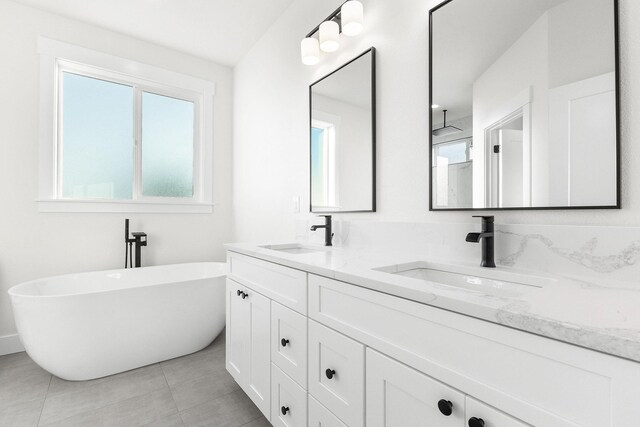 bathroom featuring a freestanding bath, double vanity, tile patterned flooring, and a sink