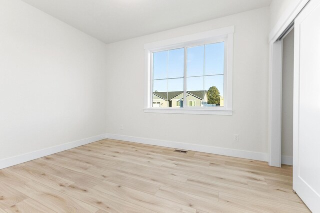 spare room featuring baseboards, wood finished floors, and visible vents