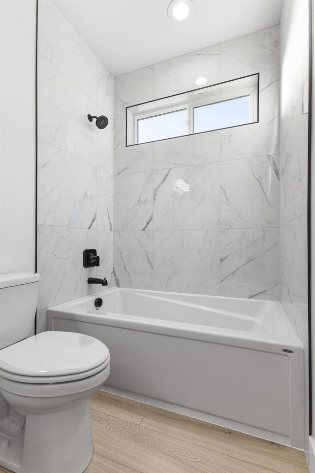 bathroom with toilet, wood finished floors, and washtub / shower combination