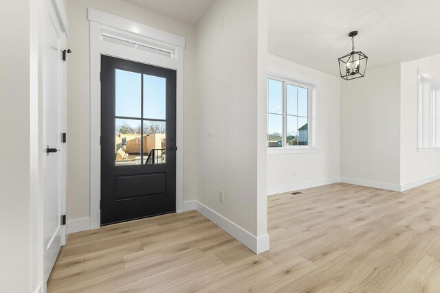 entrance foyer featuring light wood-type flooring, baseboards, and an inviting chandelier