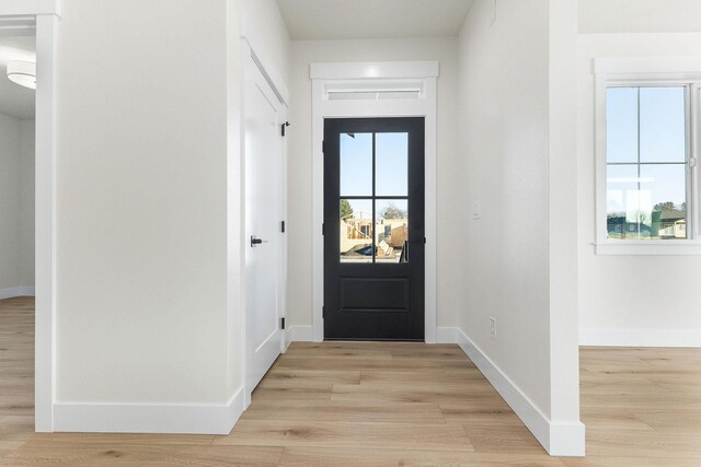doorway to outside with light wood finished floors and baseboards