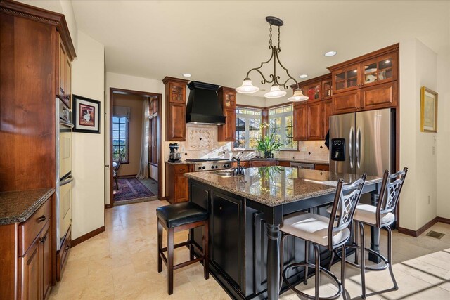 1610 E Eagle Feather Ln, Spokane, WA 99224 - kitchen featuring stainless steel appliances, backsplash, a center island with sink, baseboards, and custom range hood