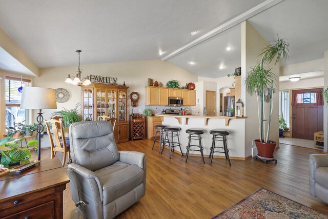 living room featuring a chandelier, light wood-style floors, and lofted ceiling with beams