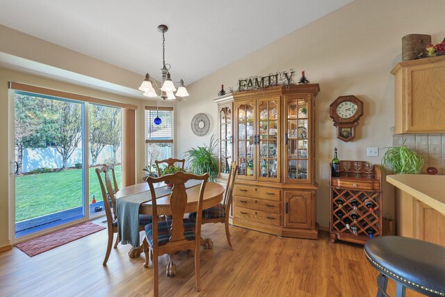 dining area featuring lofted ceiling, an inviting chandelier, and light wood-type flooring