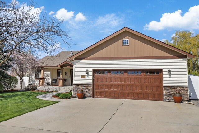 view of front of home featuring concrete driveway, a front lawn, stone siding, and covered porch