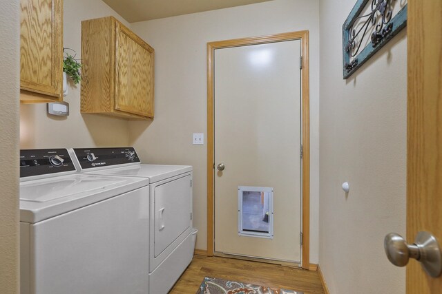 laundry area with cabinet space, light wood-type flooring, and independent washer and dryer