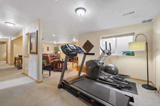 exercise area with baseboards, visible vents, and light colored carpet