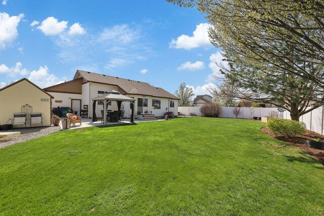 rear view of house featuring a fenced backyard, a gazebo, a yard, and a patio
