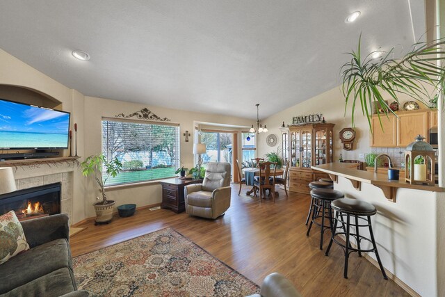 living room featuring a fireplace, vaulted ceiling, wood finished floors, and recessed lighting
