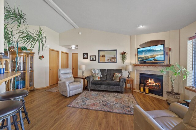 living area featuring a fireplace, wood finished floors, and vaulted ceiling with beams