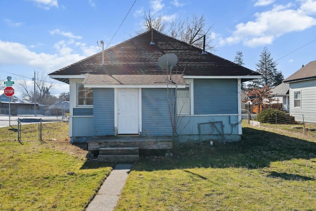 rear view of house featuring fence and a yard