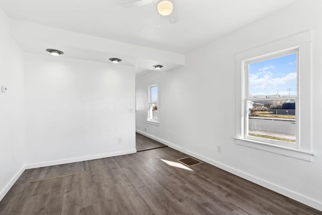 unfurnished room featuring dark wood-type flooring, visible vents, baseboards, and ceiling fan