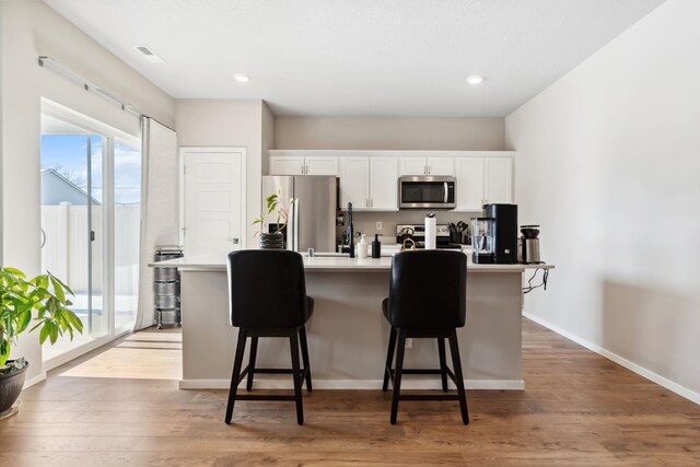 18706 E Flat Rock River Ave, Spokane Valley, WA 99016 - kitchen with an island with sink, appliances with stainless steel finishes, a breakfast bar, and white cabinetry