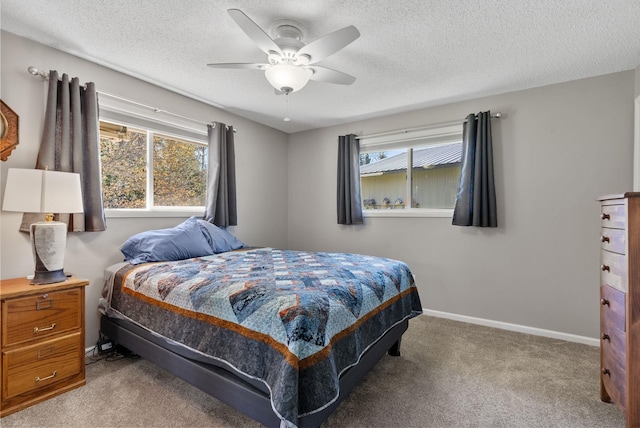 carpeted bedroom featuring ceiling fan, a textured ceiling, baseboards, and multiple windows