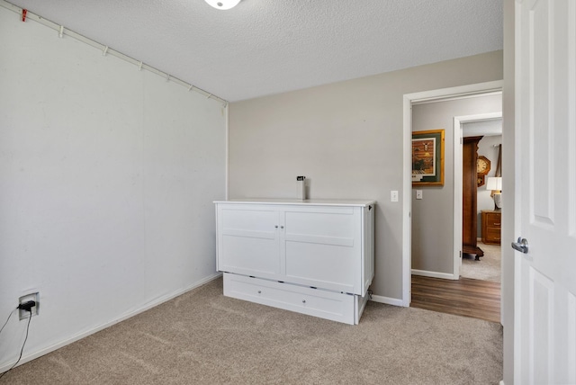 interior space featuring carpet, a textured ceiling, and baseboards