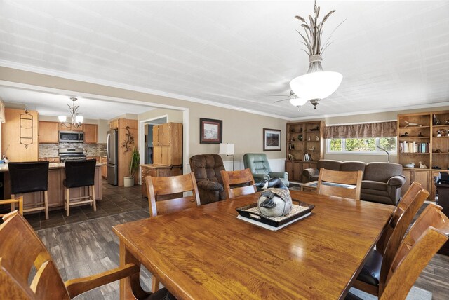 dining area featuring crown molding, dark wood-style floors, and ceiling fan with notable chandelier