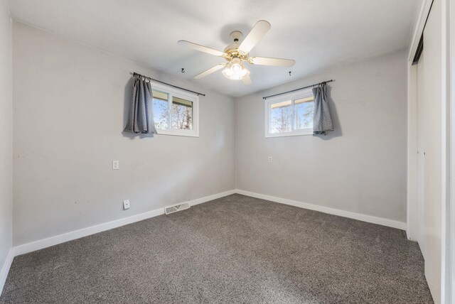 unfurnished bedroom with baseboards, dark colored carpet, and visible vents