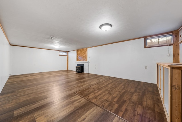 below grade area featuring visible vents, wood finished floors, a brick fireplace, and crown molding