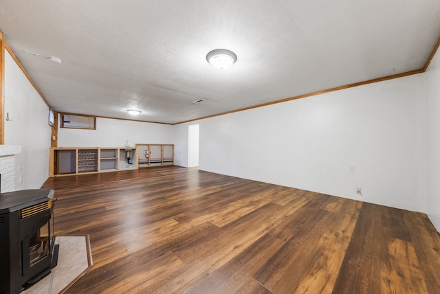 finished below grade area featuring baseboard heating, crown molding, a wood stove, and wood finished floors