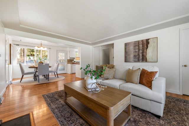 living area featuring baseboards, wood finished floors, and a chandelier