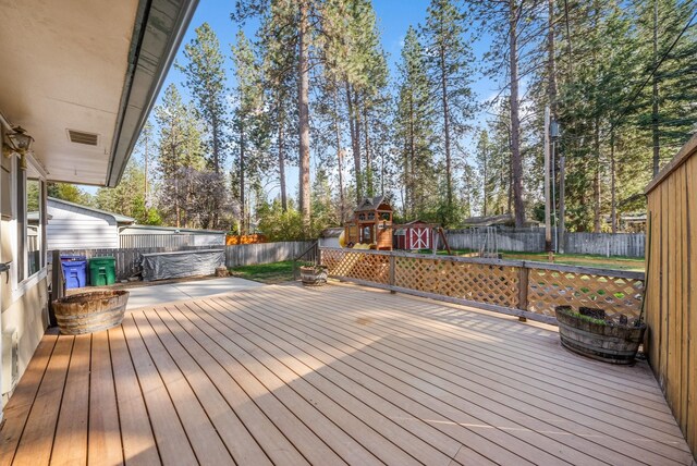 wooden deck featuring a fenced backyard, an outdoor structure, visible vents, and a shed