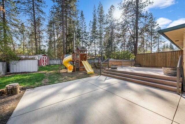 view of patio featuring fence, an outbuilding, a shed, and a playground