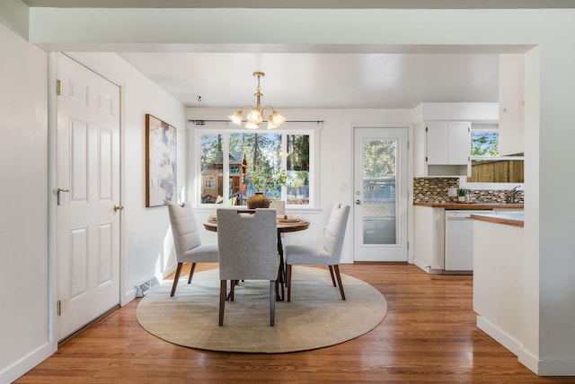dining area featuring an inviting chandelier, visible vents, light wood finished floors, and baseboards