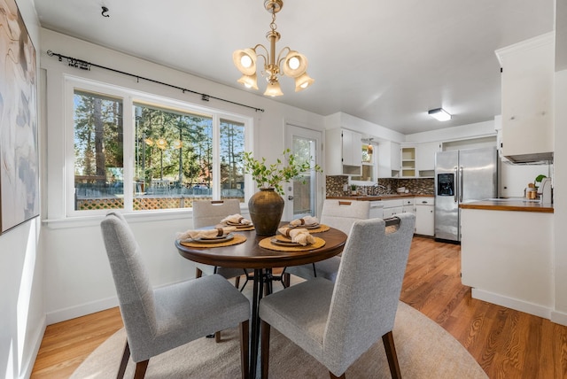 dining space featuring baseboards, a chandelier, and light wood-style floors