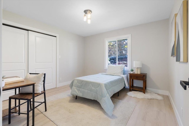 bedroom featuring light wood-type flooring, baseboards, and a closet