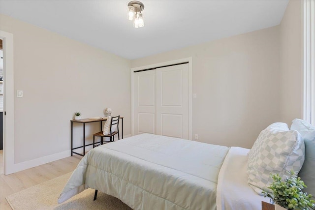 bedroom with baseboards, a closet, and light wood-style flooring