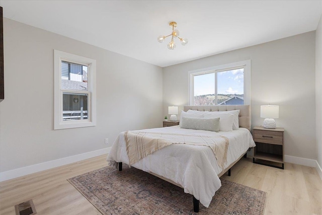bedroom featuring baseboards, a chandelier, visible vents, and light wood-type flooring