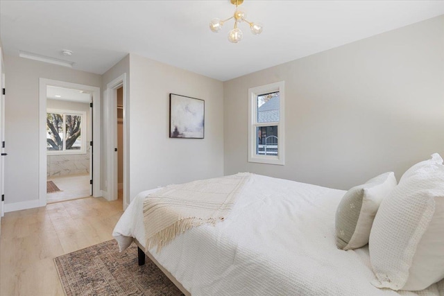 bedroom with light wood-style floors, baseboards, and an inviting chandelier
