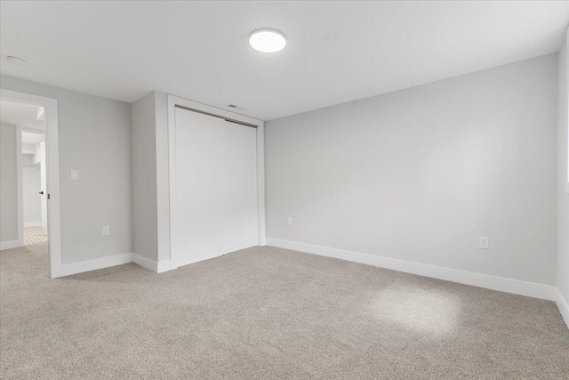 unfurnished bedroom featuring light carpet, baseboards, and a closet