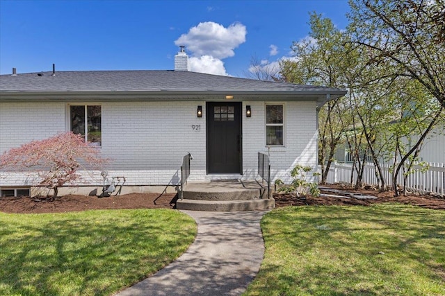 view of front of house featuring fence, a front lawn, a chimney, and brick siding