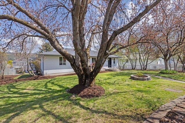 exterior space with a front lawn, brick siding, and fence