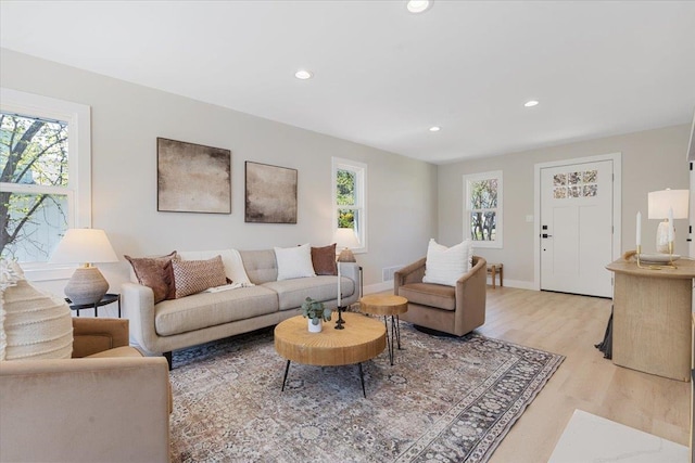 living area with recessed lighting, visible vents, light wood finished floors, and baseboards