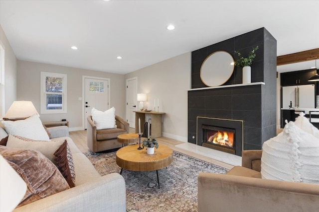 living room featuring baseboards, a tile fireplace, wood finished floors, and recessed lighting