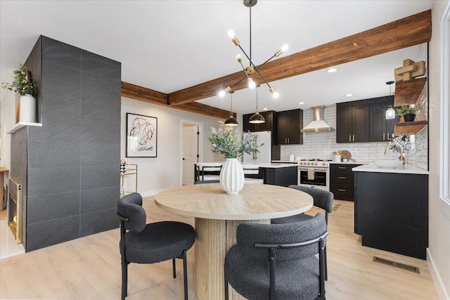 dining room with beamed ceiling, light wood-type flooring, visible vents, and baseboards