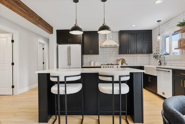 kitchen with light countertops, wall chimney exhaust hood, decorative backsplash, and white appliances