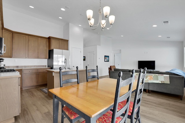 dining space featuring recessed lighting, an inviting chandelier, light wood-style floors, and high vaulted ceiling