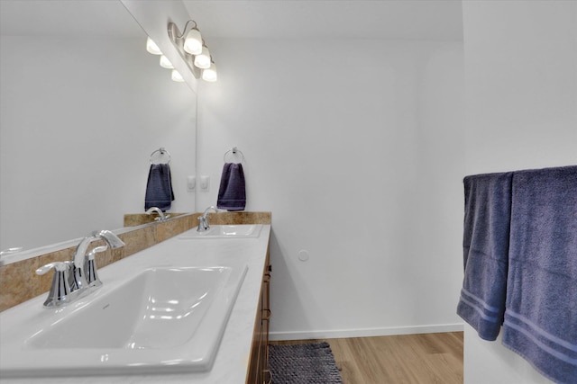bathroom featuring baseboards, wood finished floors, a sink, and double vanity