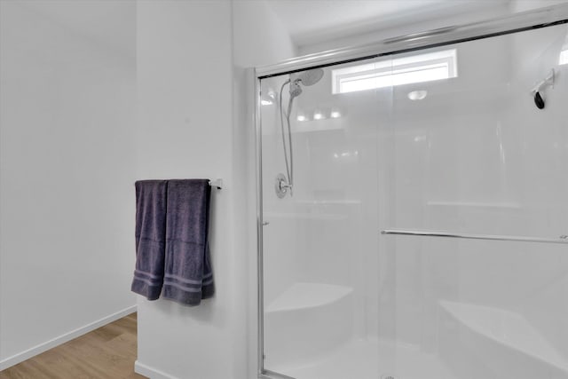 bathroom featuring a shower stall, baseboards, and wood finished floors