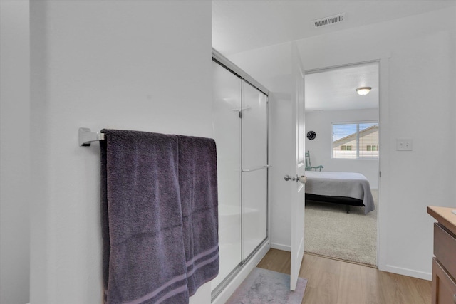 ensuite bathroom with wood finished floors, visible vents, vanity, ensuite bath, and a stall shower