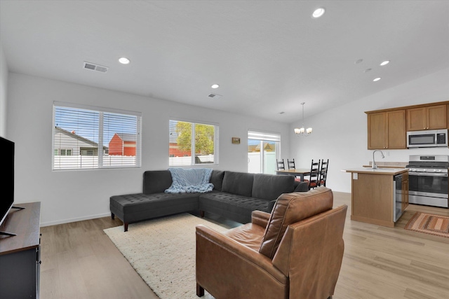 living area with light wood-type flooring, vaulted ceiling, visible vents, recessed lighting, and a notable chandelier