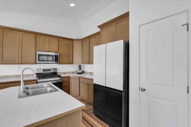 kitchen with a sink, recessed lighting, brown cabinets, light countertops, and appliances with stainless steel finishes