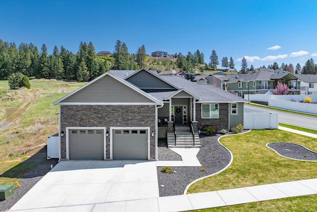 ranch-style home featuring a front lawn, driveway, fence, and stone siding